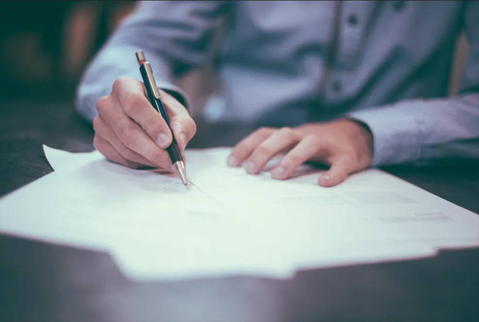 Conseiller écrivant et signant des documents administratifs pour l'organisation des obsèques.
